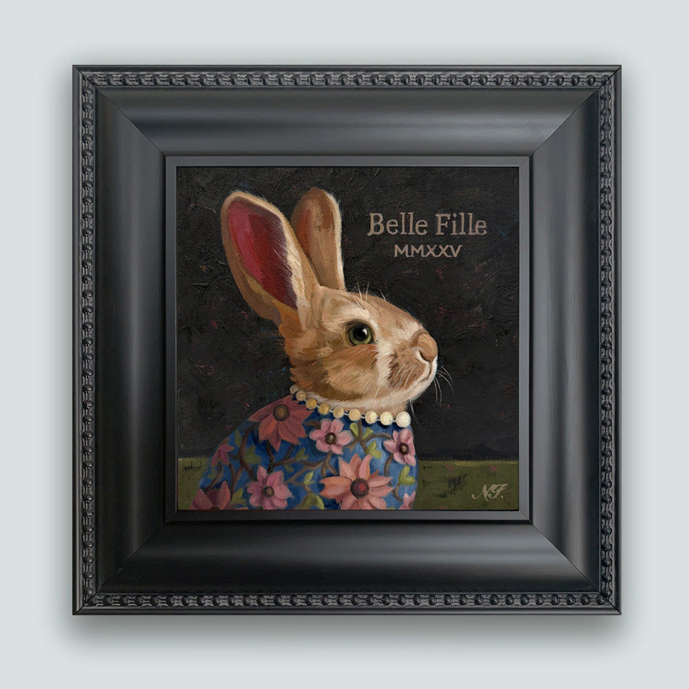 Belle Fille (Beautiful Girl) rabbit painting by Ninalee Irani. Portrait of a rabbit wearing a floral shirt and pearls, set in a black frame. Shown on pale blue wall.