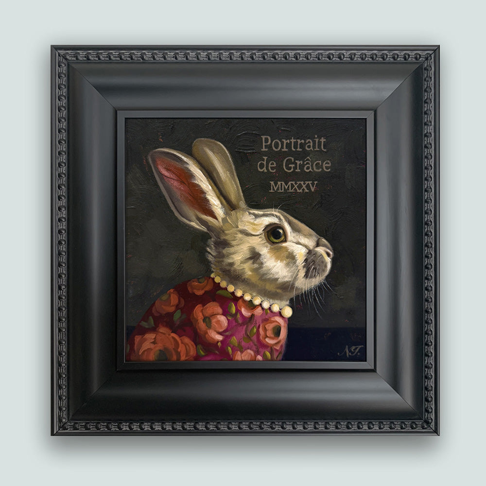 Portrait of Grace rabbit painting by Ninalee Irani. Portrait of a rabbit wearing a floral shirt and pearls, set in a black frame. Shown on pale blue wall.