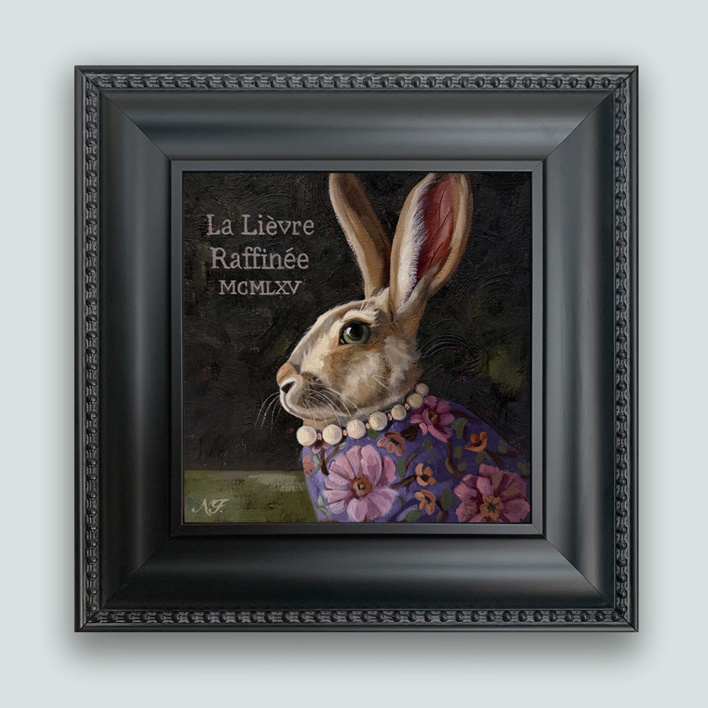 The Refined Hare rabbit painting by Ninalee Irani. Portrait of a rabbit wearing a floral shirt and pearls, set in a black frame. Displayed on pale blue wall.
