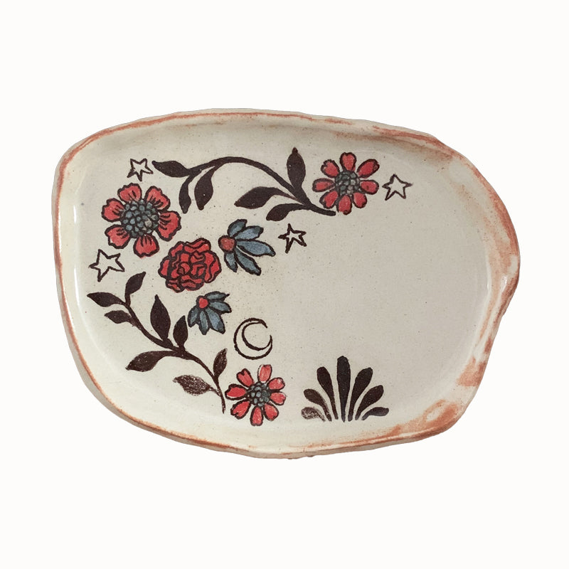 Handmade pottery from Off Menu Pots. Small dish decorated with red and blue flowers, and a crescent moon.