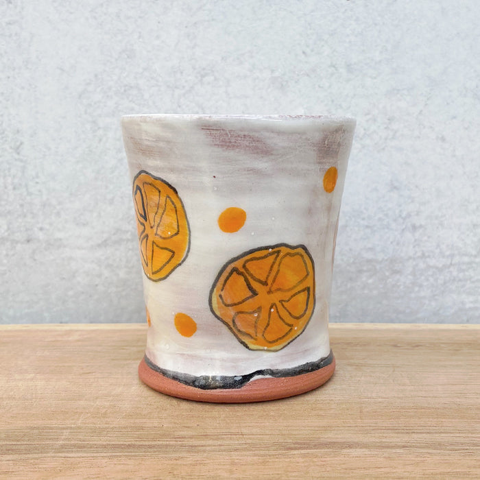 Handmade ceramic cup by NC potter Molly Lithgo. White with orange slice and polka dot decoration. 