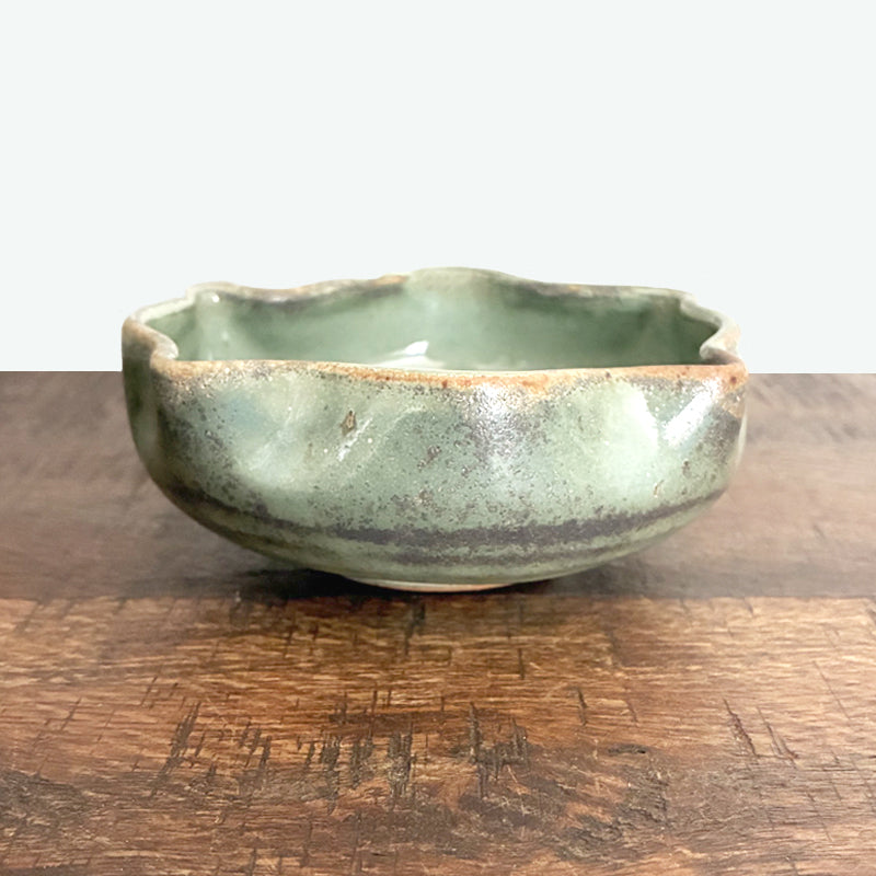 Small fluted, handmade snack bowl, pale muted green with rustic details.  Exterior view. 