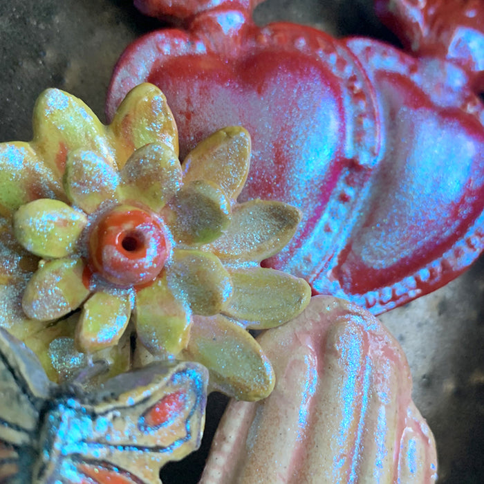 Hand and Hearts ceramic wall niche by Paula Smith. Decorative wall art featuring a hand, hearts and flowers. Detail shown.