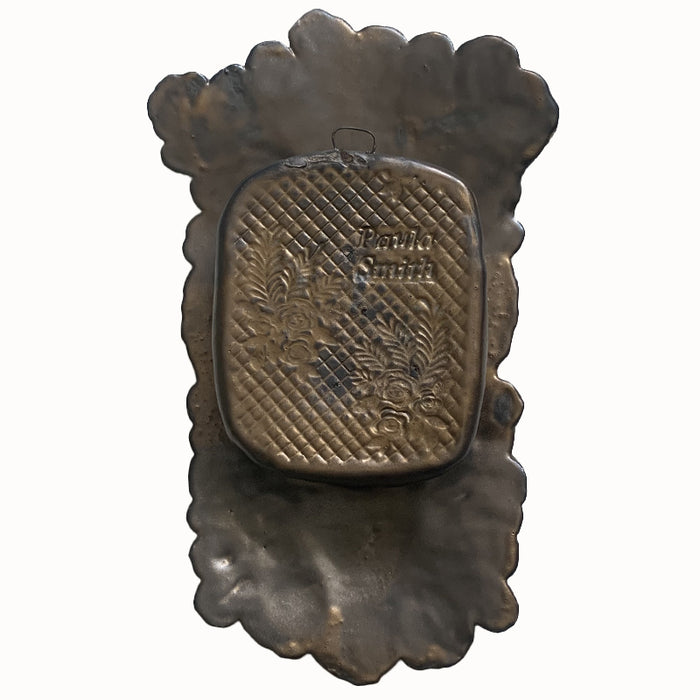 Handmade ceramic wall niche by Paula Smith. Clay face is stamped with flower and bee patterns and a hand pattern, finished in a gunmetal glaze. Red flower details are in the face, with three dimensional yellow light blue flowers with leaves in the center. Back view for hanging.