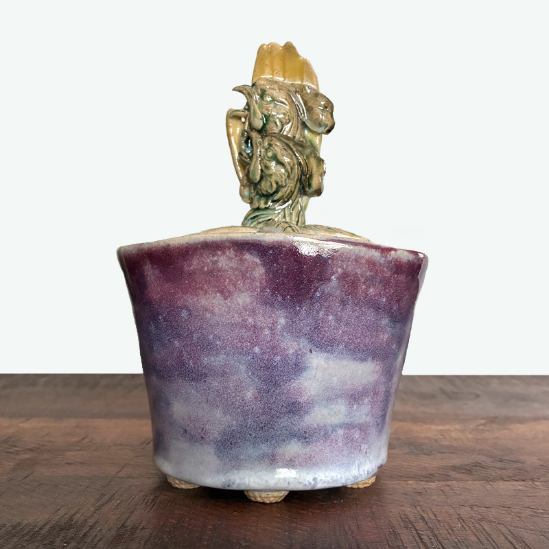 Purple handmade ceramic lidded jar with hand, rooster and flower details.  Back view. 