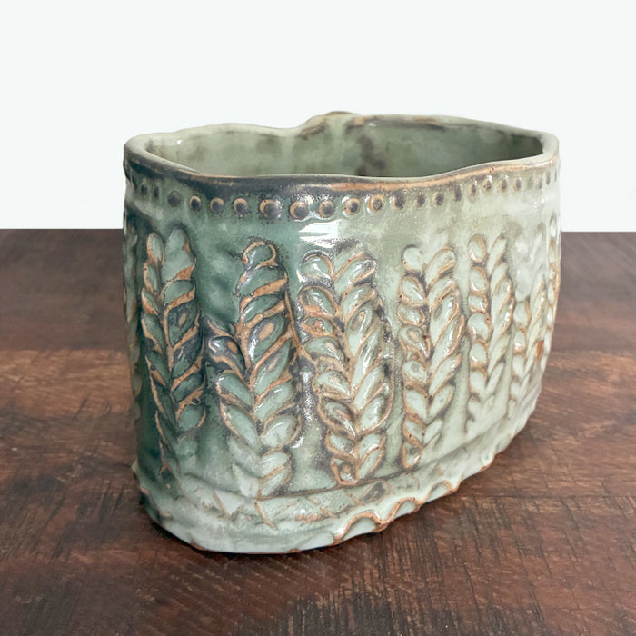 Handmade ceramic oval container with texture details. Back side view. 