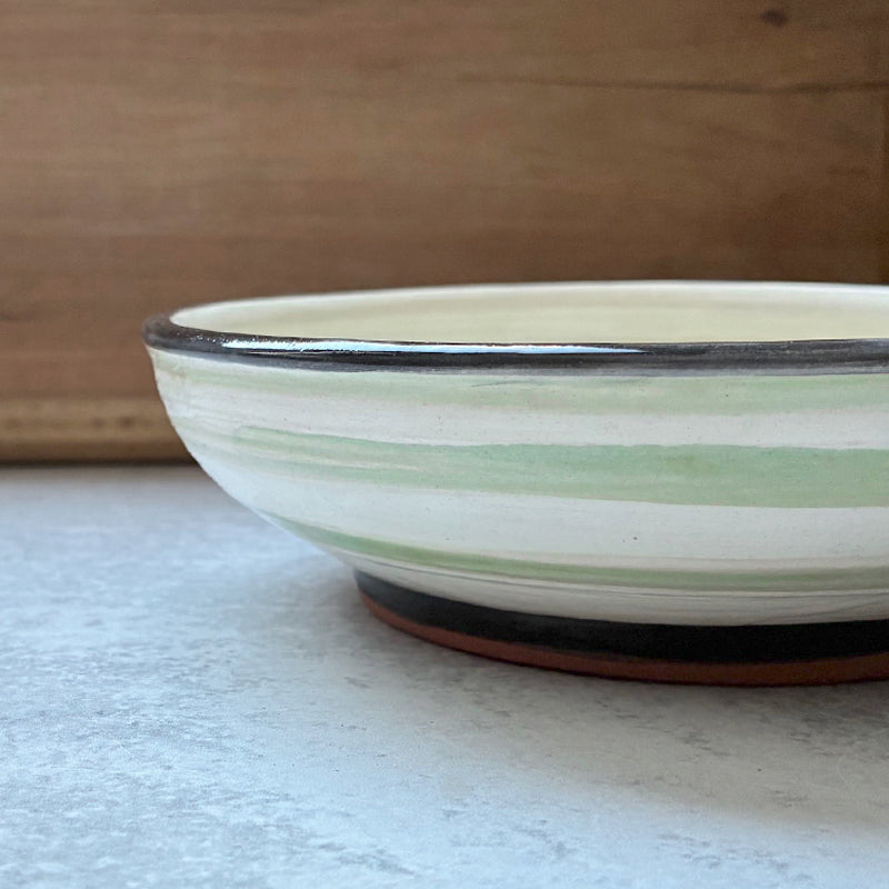 Handmade ceramic bowl with green peas in pods decoration on the interior by artist Molly Lithgo. Side view.