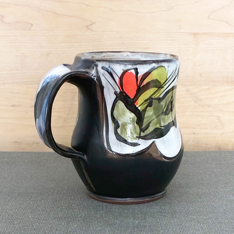 Handmade ceramic mug, black and white with abstracted orange and chartreuse floral with green leaves by Renata Copeland. 