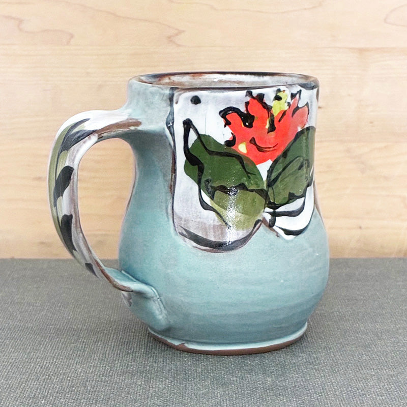 Handmade ceramic mug, light blue and white with bright orange floral design by Renata Copeland. 
