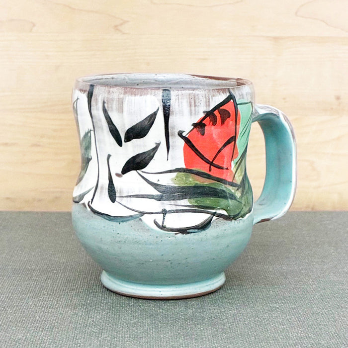 Handmade ceramic mug, light blue and white with bold orange and aqua floral design by Renata Copeland. 