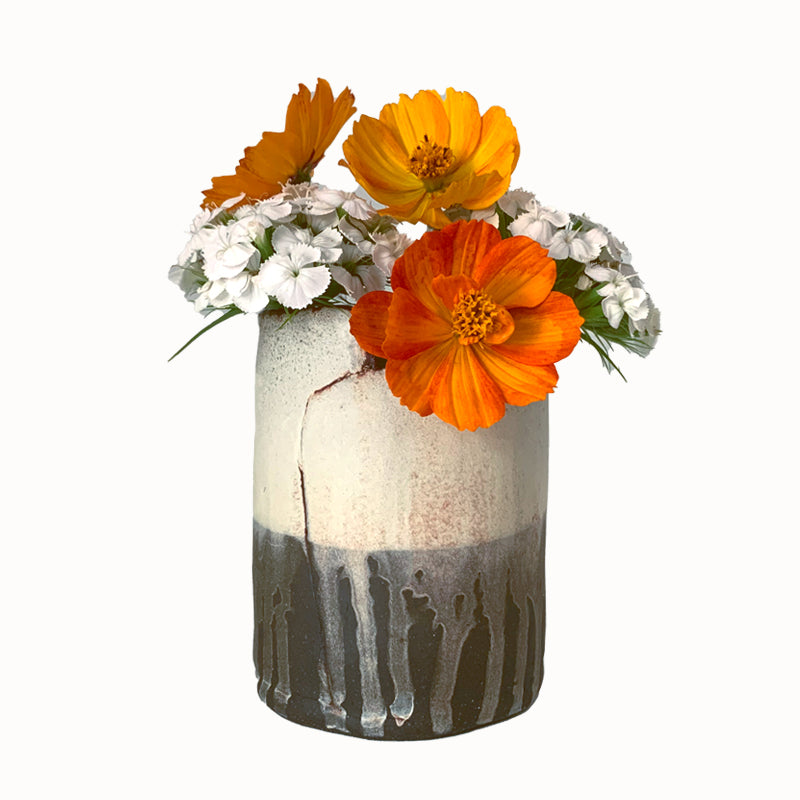 Small dark brown and white drippy vase by ceramic artist Robin Ralston Frelier. Shown with orange and white flowers.