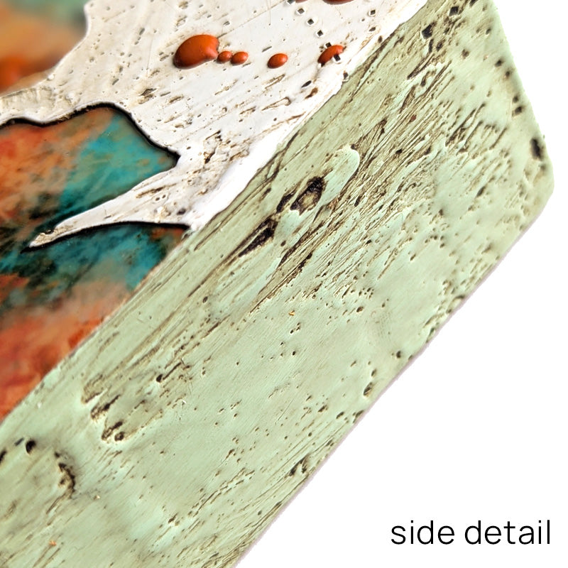 Bloom No. 14, small mixed media painting by artist Sarah Treanor. Orange and aqua textural, floral artwork created with digital prints of the  artist's cyanotypes and eco prints underneath layers of encaustic paint, with splatters of orange encaustic on top. Side detail shown.