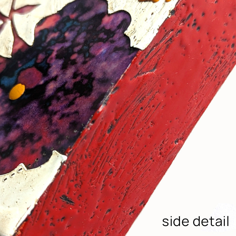 Bloom No. 16, small mixed media painting by artist Sarah Treanor. Red and purple textural, floral artwork created with digital prints of the  artist's cyanotypes and eco prints underneath layers of encaustic paint, with splatters of orange encaustic on top. Side detail shown.