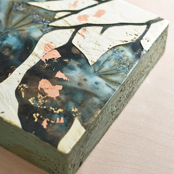 Midnight Embers II mixed media encaustic leaf artwork in rich blues with gold and copper leaf details. Side view. 