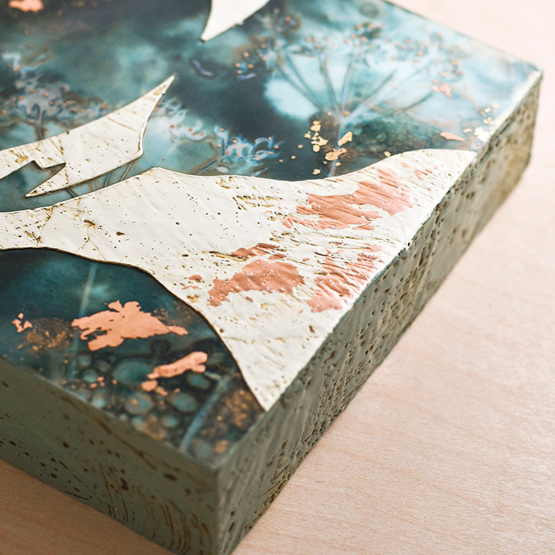 Midnight Embers III mixed media encaustic leaf artwork in rich blues with gold and copper leaf details. Side detail.