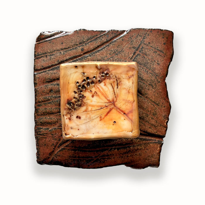 Irregular shaped and textured brown ceramic tile, with mixed media floral design in the center. Artwork by Sarah Treanor.