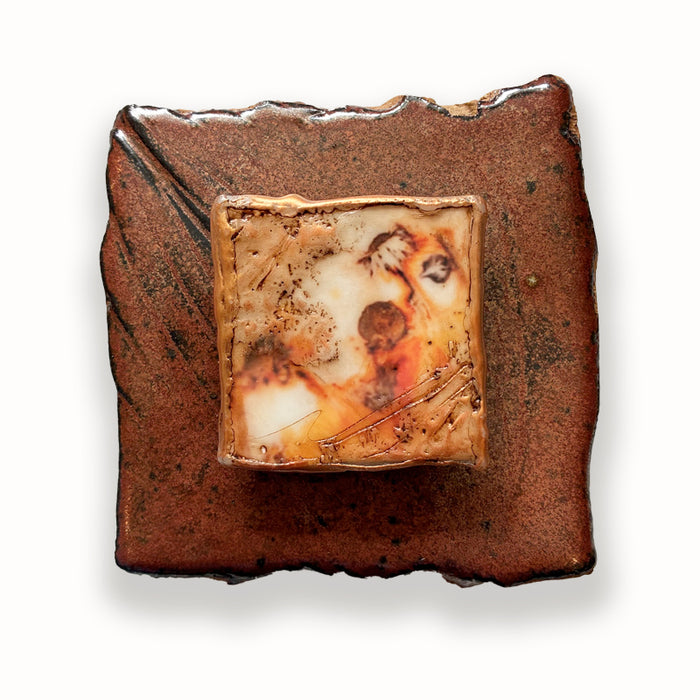 Irregular shaped ceramic tile in brown hues, with mixed media floral design in the center. Artwork by Sarah Treanor.