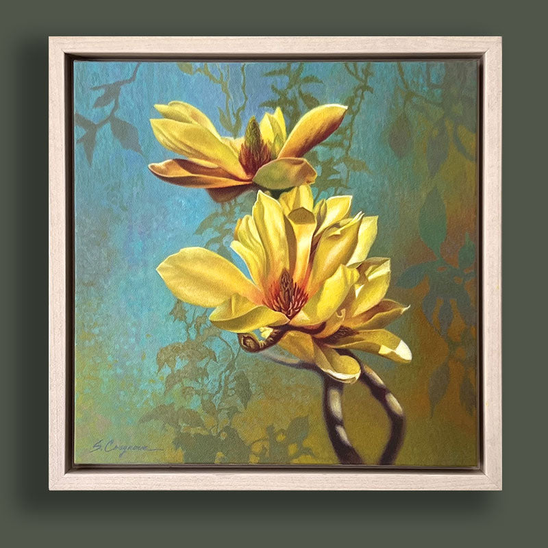 Oil painting featuring two bright yellow magnolia flowers  against a textured blue and green botanical background. The artwork, by Sharon Cosgrove, is set in a hardwood maple frame and displayed on dark green wall. 