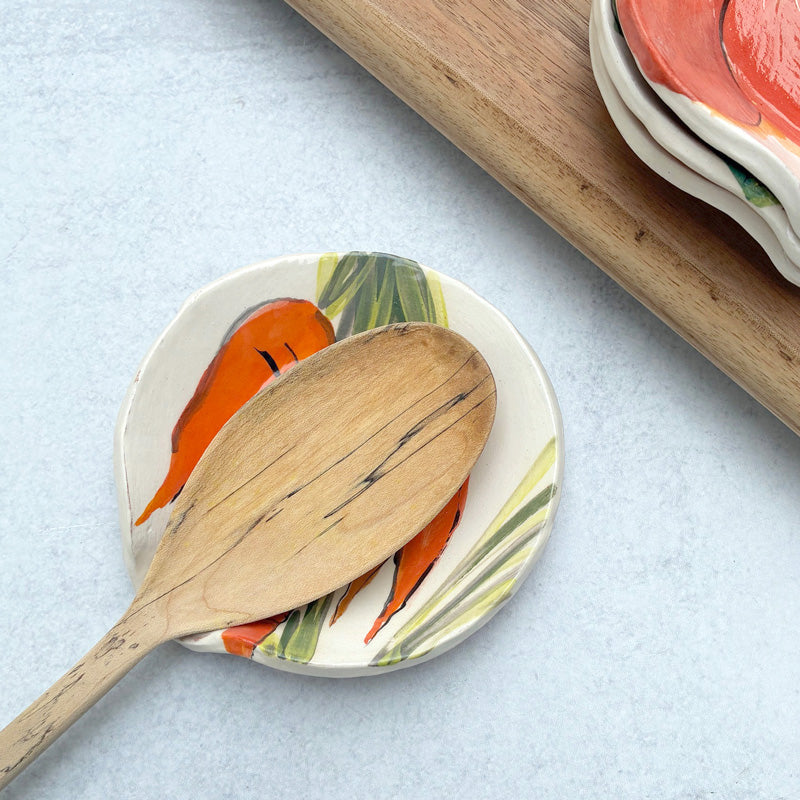 Handmade ceramic spoon rest with apple decoration by artist Molly Lithgo. Image shows wooden spoon on spoon rest.