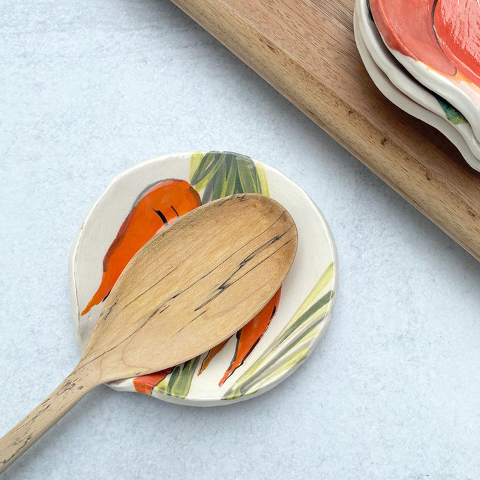 Handmade ceramic spoon rest with apple decoration by artist Molly Lithgo. Image shows wooden spoon on spoon rest.