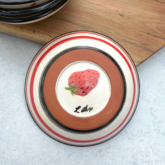 Handmade ceramic bowl with strawberry decoration on the interior by artist Molly Lithgo. Bottom view with stripes on a strawberry on base.