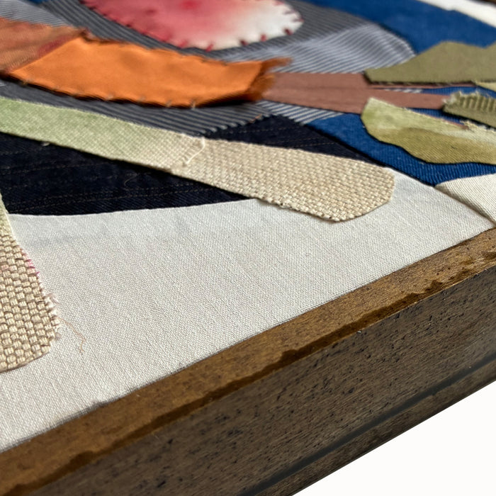 Veggie Plate textile collage by artist Hannah Goff. The artwork is comprised of hand-sewn and painted, reclaimed and recycled fabrics. It features a carrot, radishes and green onions on a blue plate. Finished in a handmade rustic wood frame. Close up detail, side view.